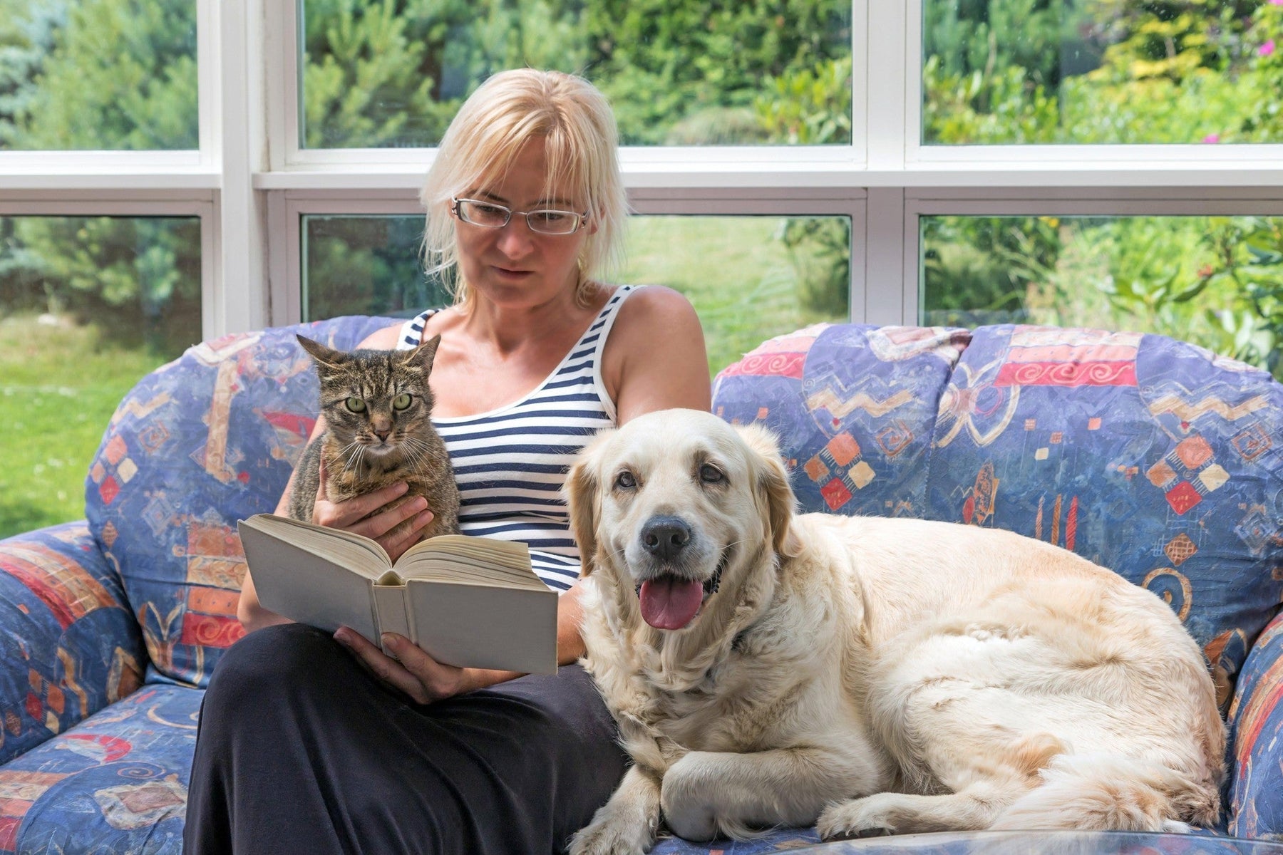 woman reading with senior dog and cat