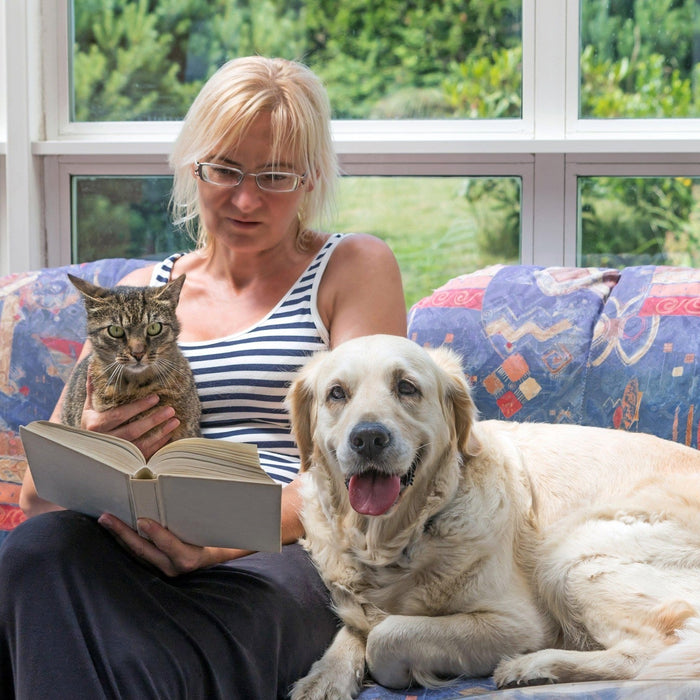 woman reading with senior dog and cat